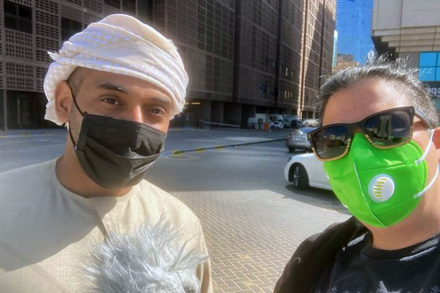 Mohamed Al Jneibi and Diana Chester, both wearing face masks, pose on a city street.