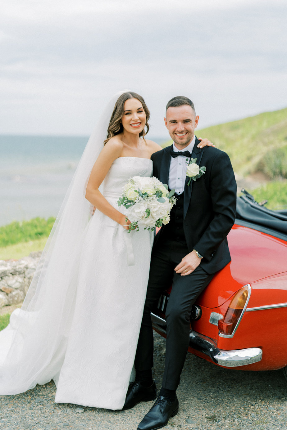 Bride groom sitting on red wedding car sea beach landscape