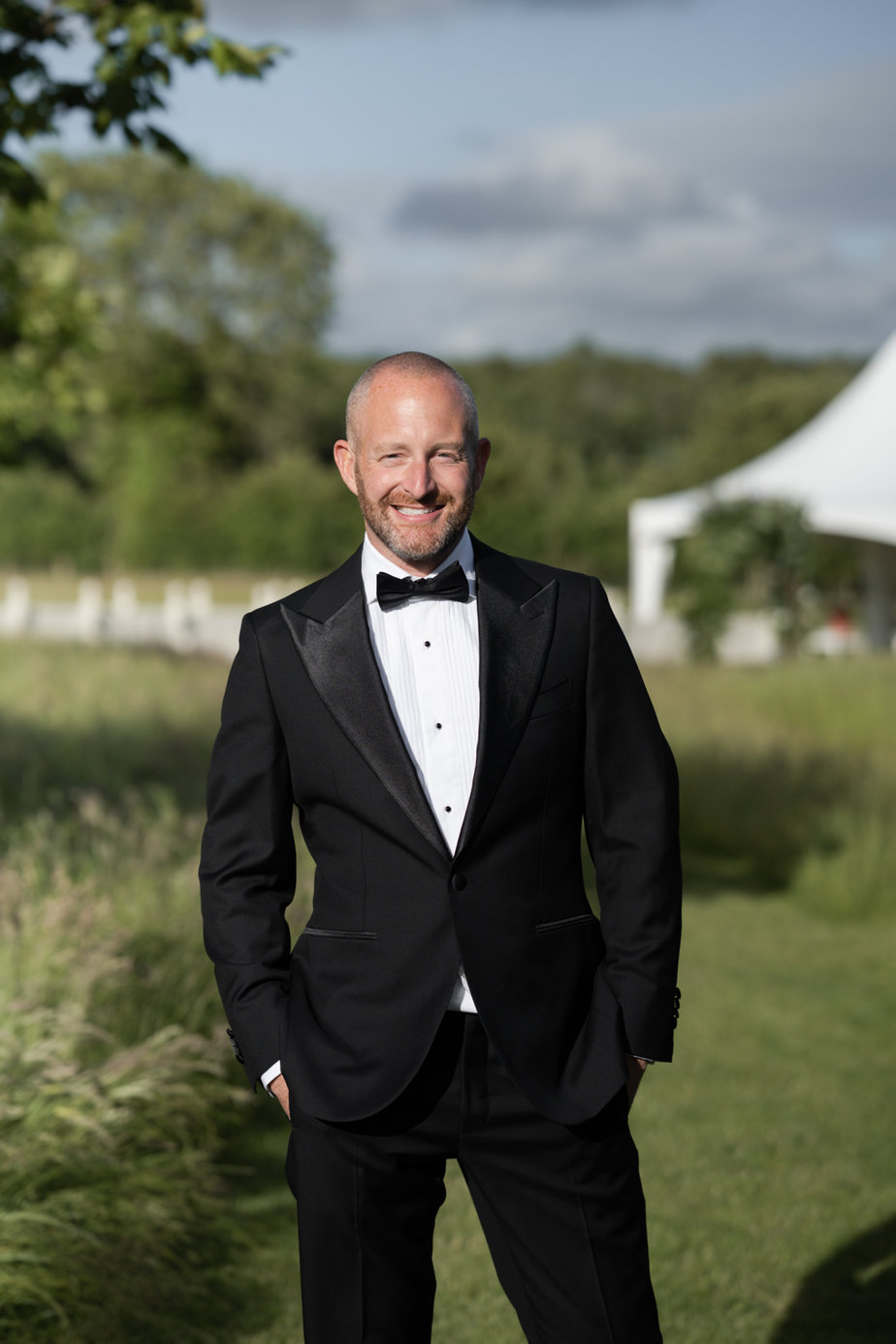 Groom wearing black suit and tie garden marquee