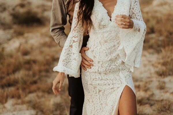 A bride wearing a lace wedding dress with bell sleeves. 