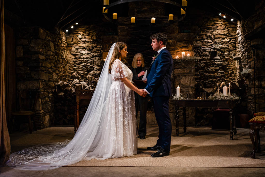 Bride and groom hold hands at alter during ceremony