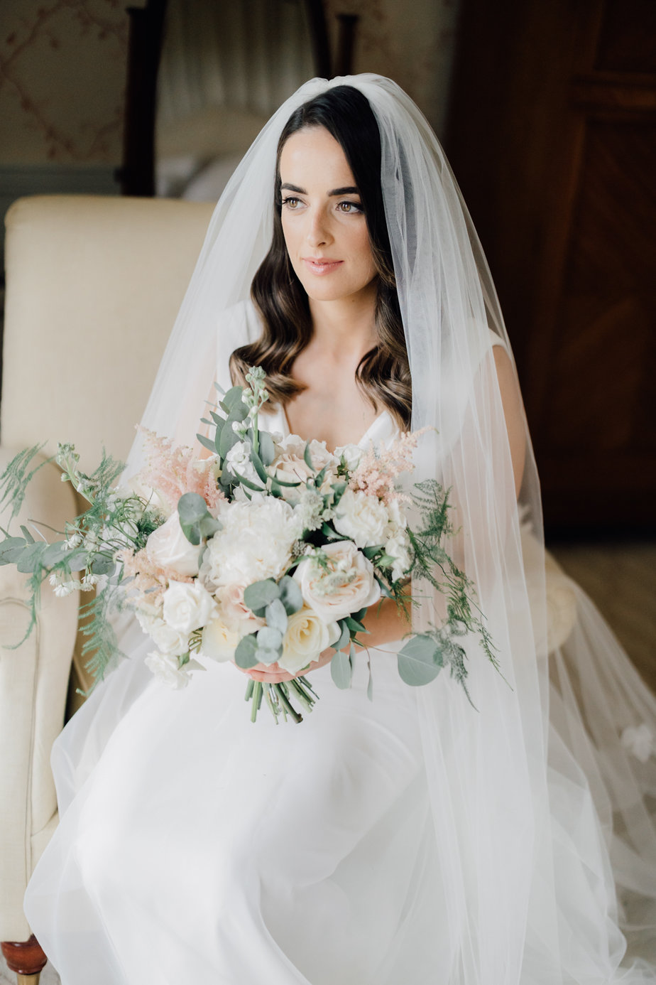 bride in dress veil and holding bouquet 