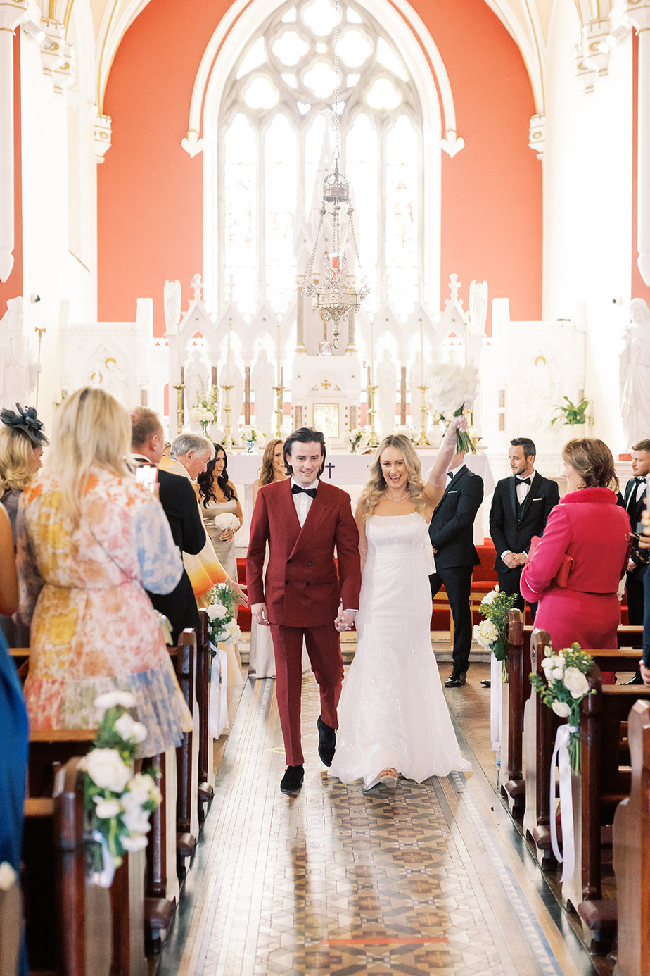 Bride and groom walking down the aisle surrounded by guests in church