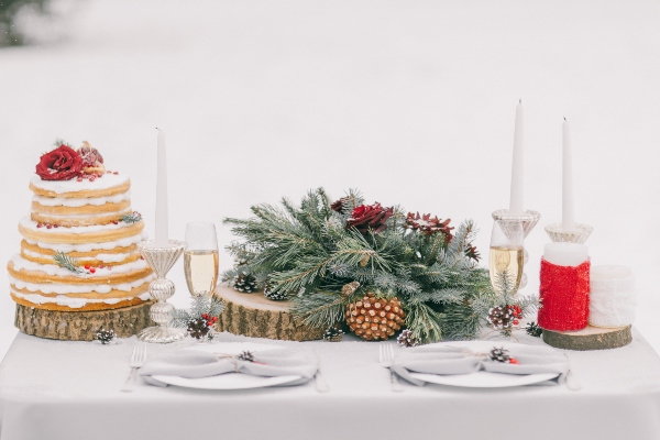 A table at a winter wedding with a cake and greenery.