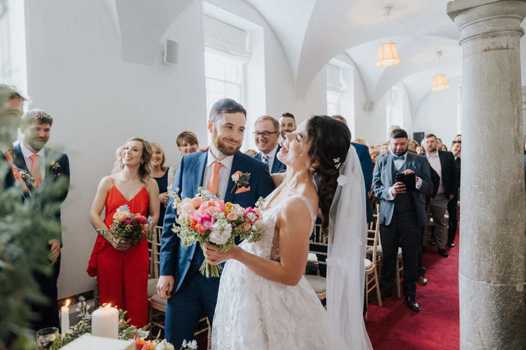 Bride and groom in front of guests holding flowers