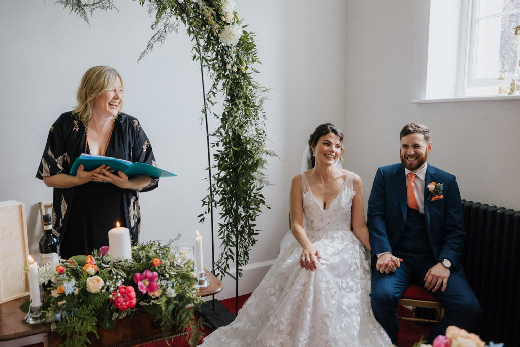 Bride and groom officiant sitting down in front of guests