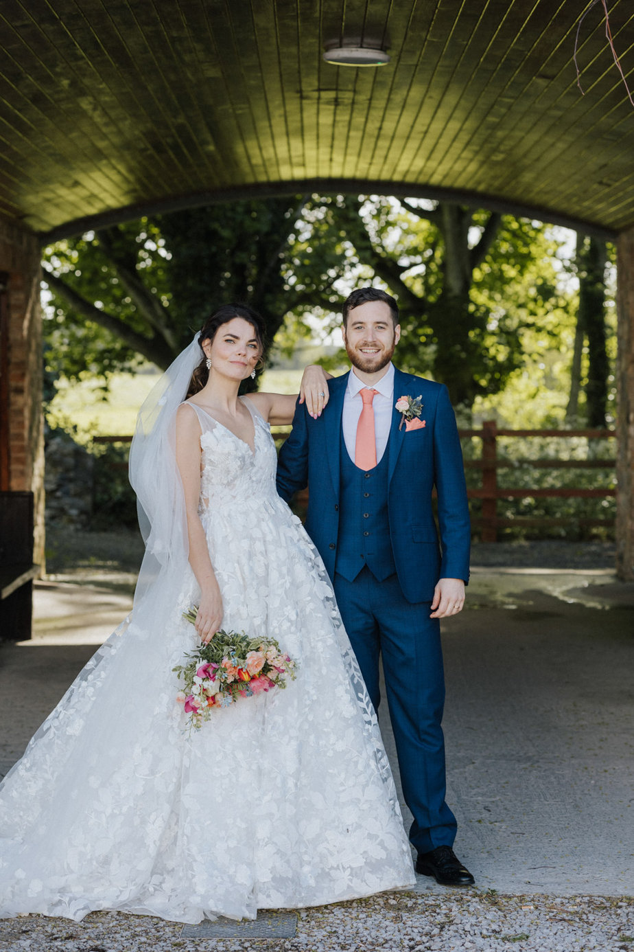 Bride and groom facing camera farm trees in background