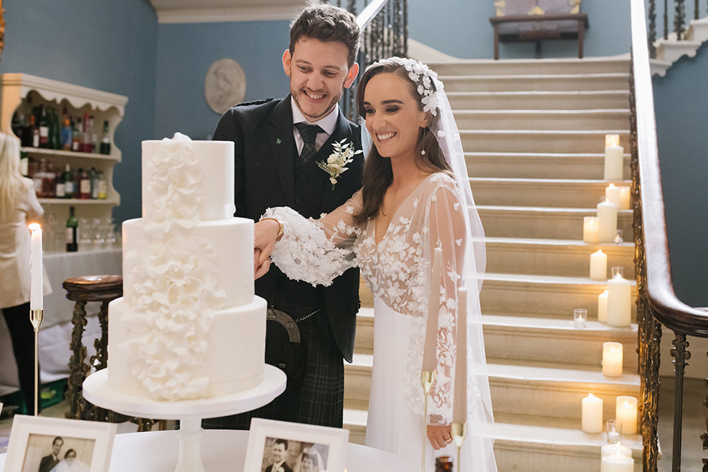 Bride and groom cut the wedding cake lace dress detail