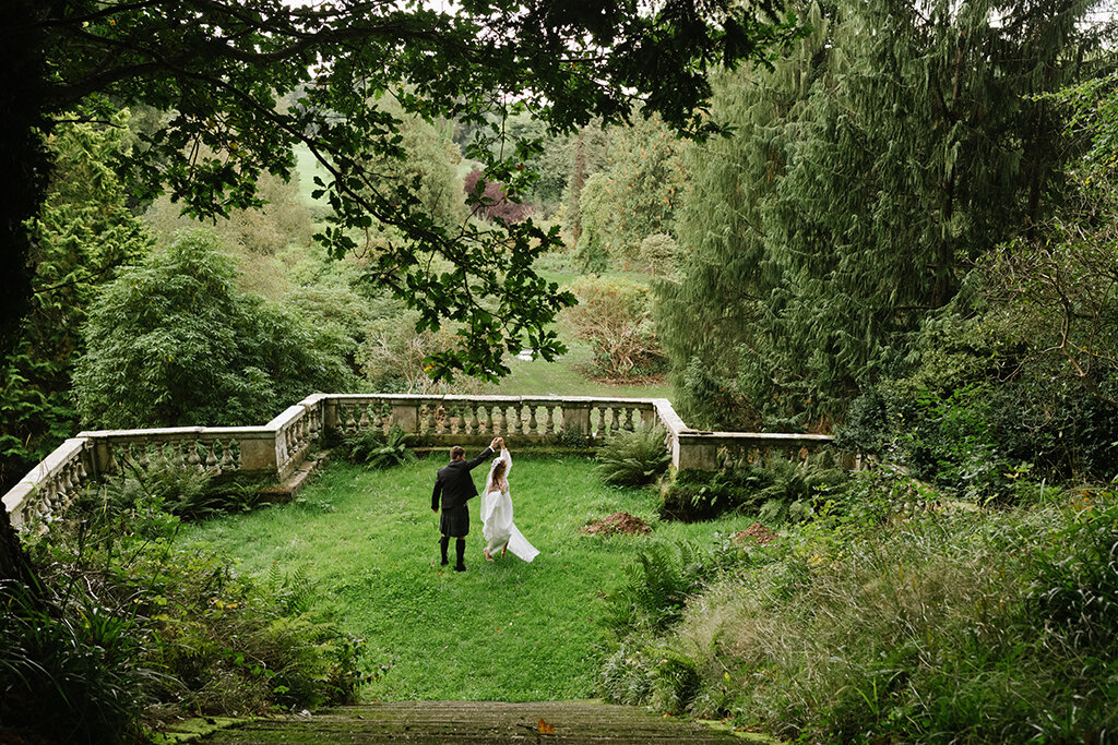 Bride and groom walking in garden lace dress veil detail steps