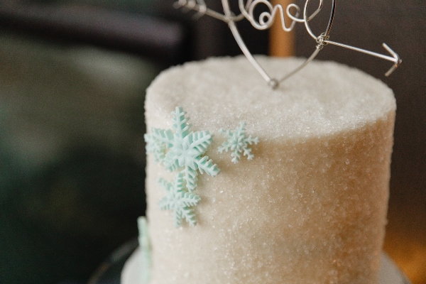 A wedding cake decorated with an icing snowflake and a cake topper that says 