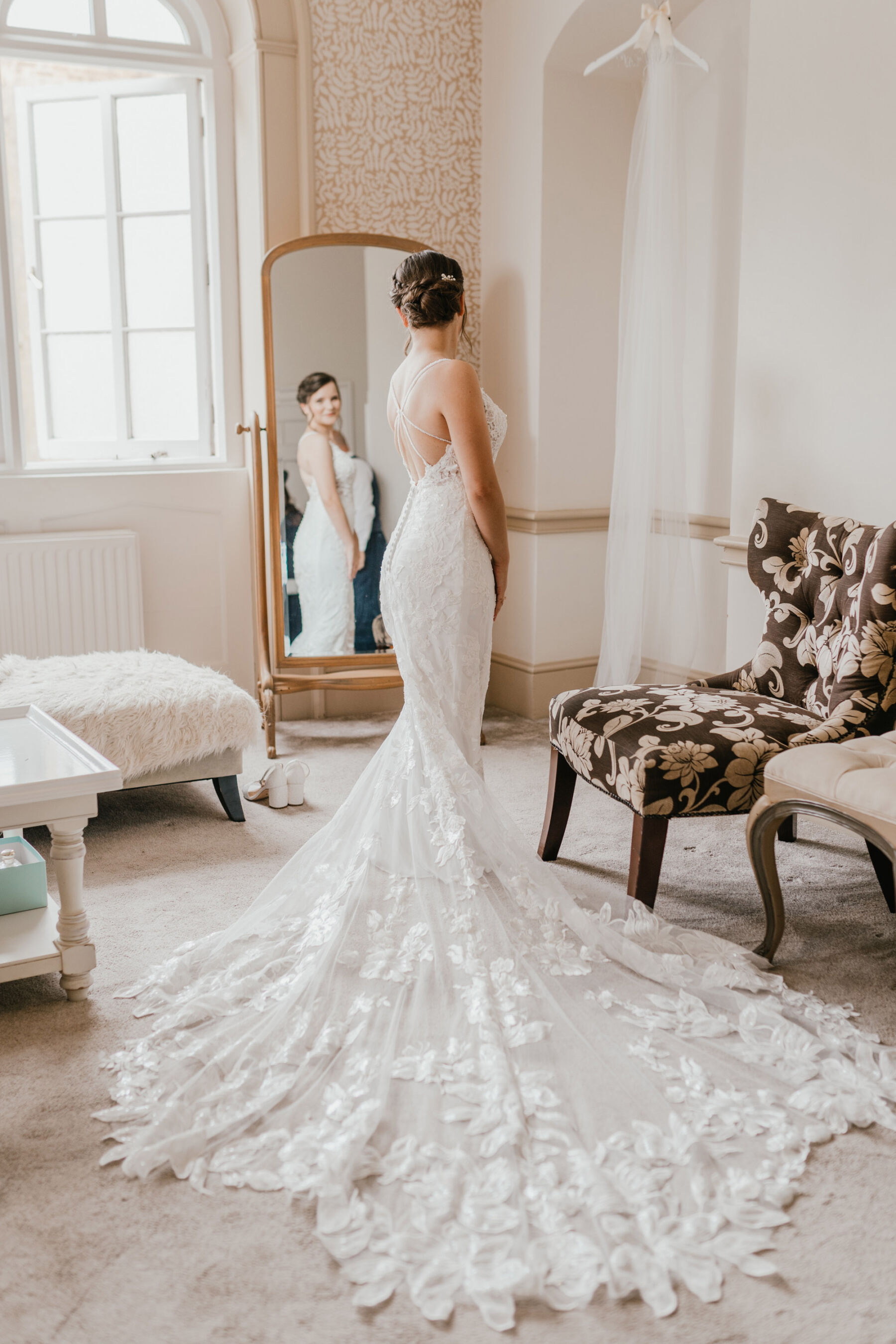 Bride wearing an Essense of Australia wedding dress with long elegant train, looking into the mirror at Nonsuch Mansion. Shelby Ellis Photography.