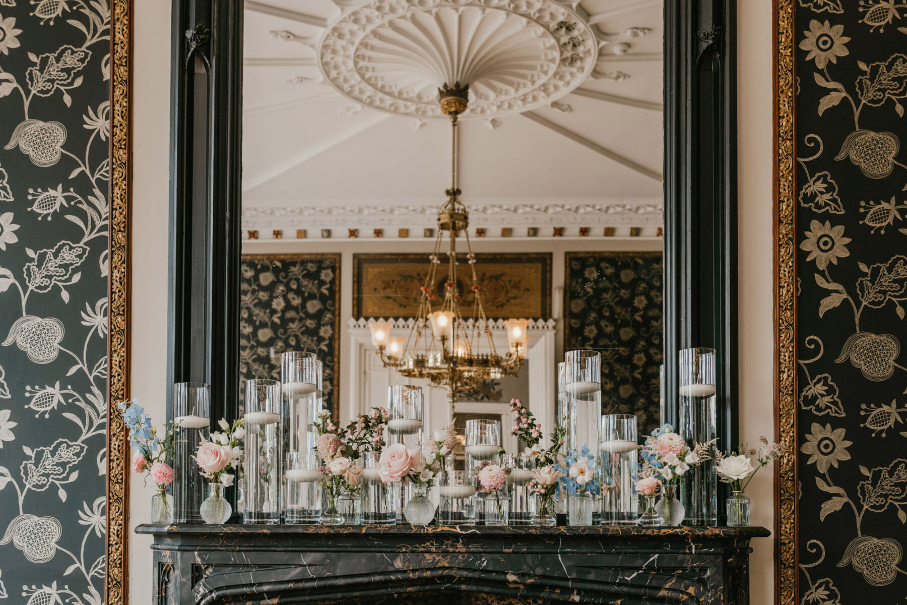 Pretty glass bud vases on fireplace mantel, with pale pink roses, Nonsuch Manor wedding venue. Shelby Ellis Photography.