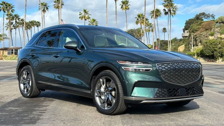 2024 Genesis Electrified GV70 in green parked in a beach parking lot.
