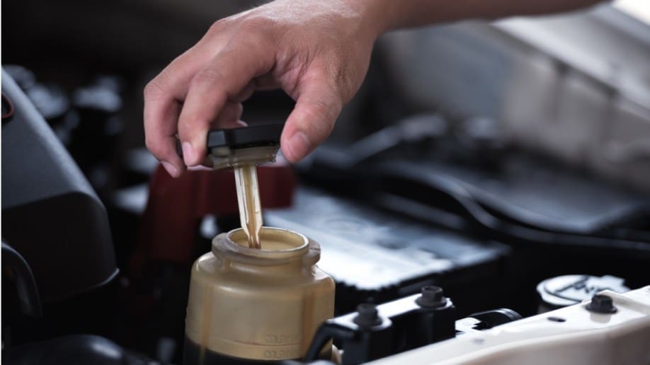 A person checking a car's power steering fluid