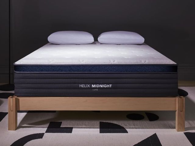 Helix Sleep Midnight, a thick mattress with dark blue trim, sitting on a minimalist wooden bed