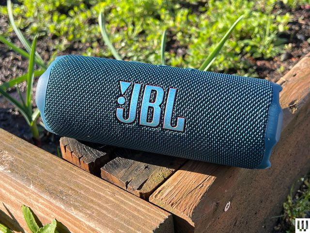 Front view of J.B.L. Flip 7 Bluetooth Speaker sitting on wooden edge of garden box.