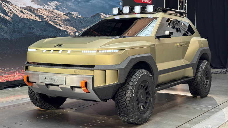 A front three quarters shot of the Crater concept parked in the XRT studio in front of a photo of mountains