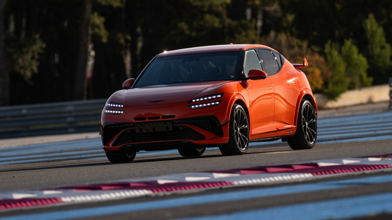 Front 3/4 view of an orange Genesis GV60 Magma on track