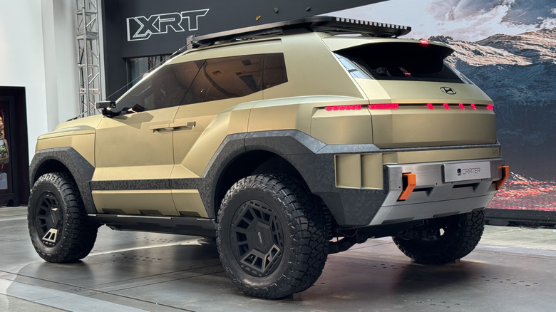 A rear three-quarters shot of the Crater concept in the XRT studio in front of a photo of mountains and a sign that says XRT