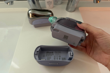 Leah's hand holding Shark FacialPro Glow attachment above battery pack