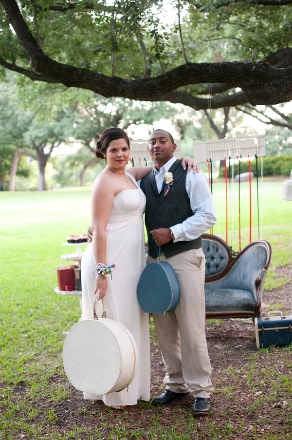 Bride in simple white column gown with straps at an outdoor elopement, holding vintage hat boxes with groom