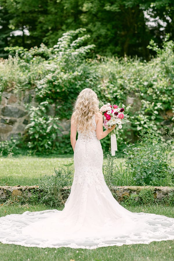 Back view of bride in sleeveless high-neck embroidered lace fit-and-flare wedding gown standing in garden at private estate in Michigan