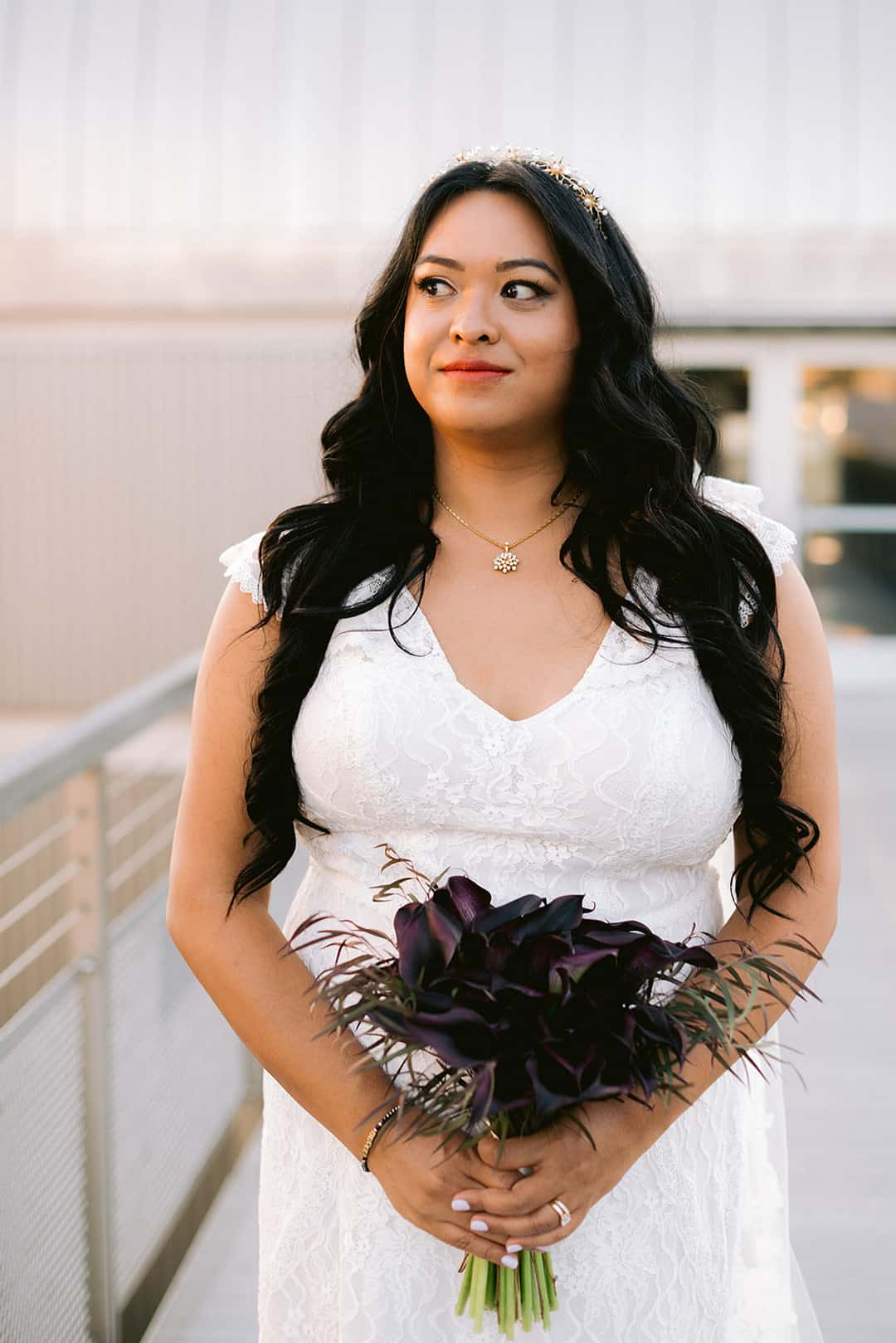Bride at Chabot Space and Science Center holding a tight architectural bundle of deep black-purple calla lilies with dark wispy botanical accents