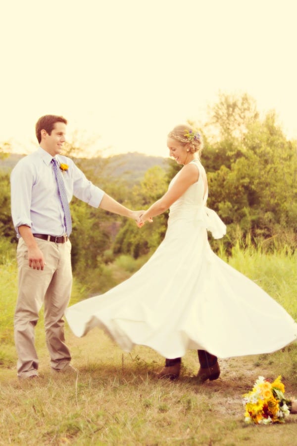 Bride in flowing white a-line wedding gown twirling and dancing with groom in a sunlit field at Cedarwood Nashville outdoor wedding