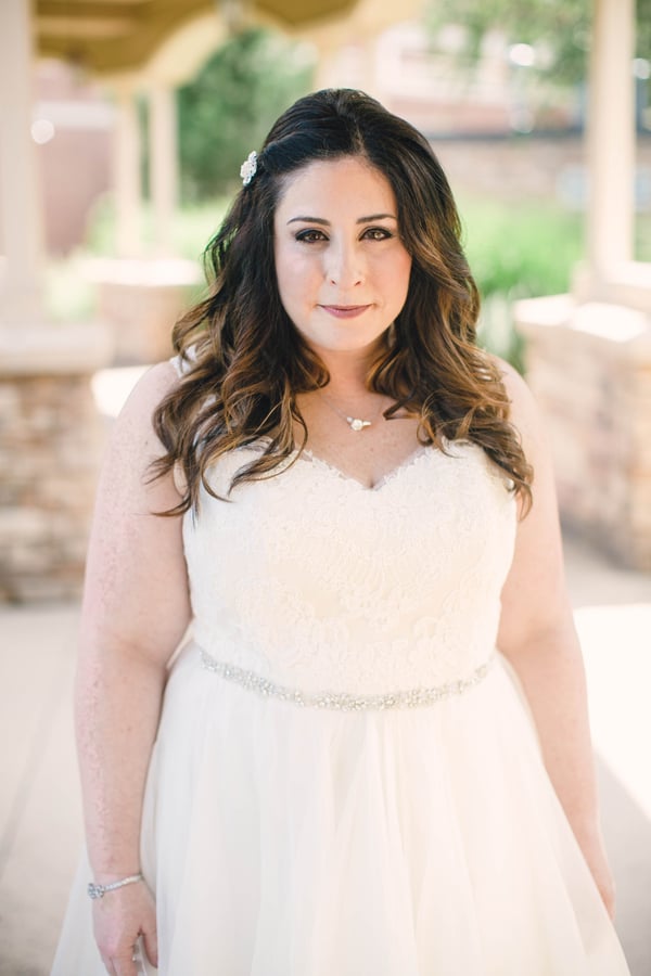 Plus-size bride in ivory strapless sweetheart gown with lace bodice and crystal waist belt in a close-up bridal portrait