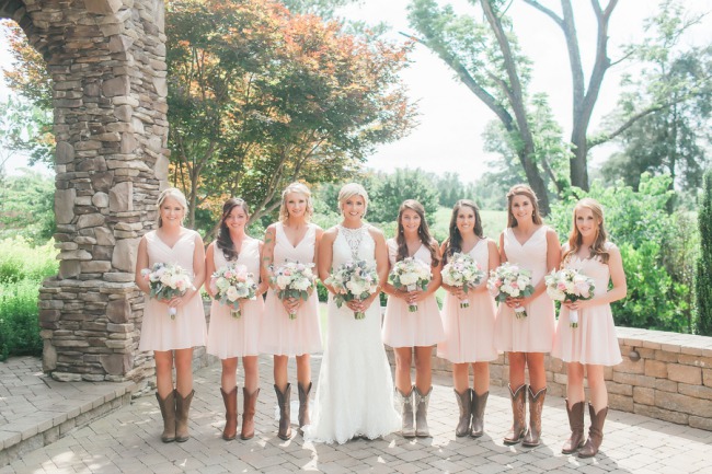 Bride in sleeveless high-neck lace wedding gown with bridesmaids in blush dresses and cowgirl boots at The Arbors Events North Carolina