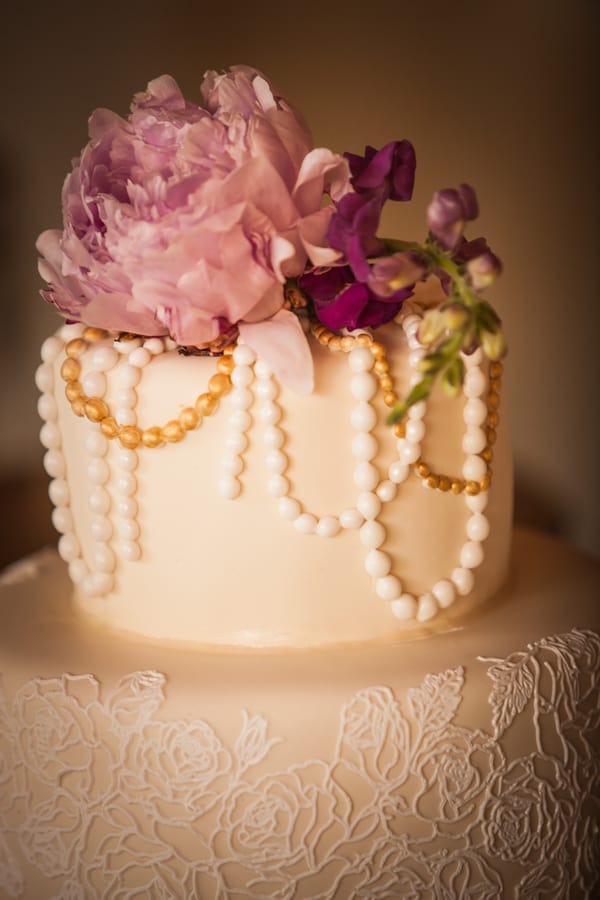 Close-up of ivory wedding cake tier with draped pearl fondant swags, delicate floral icing accents, and intricate surface detail