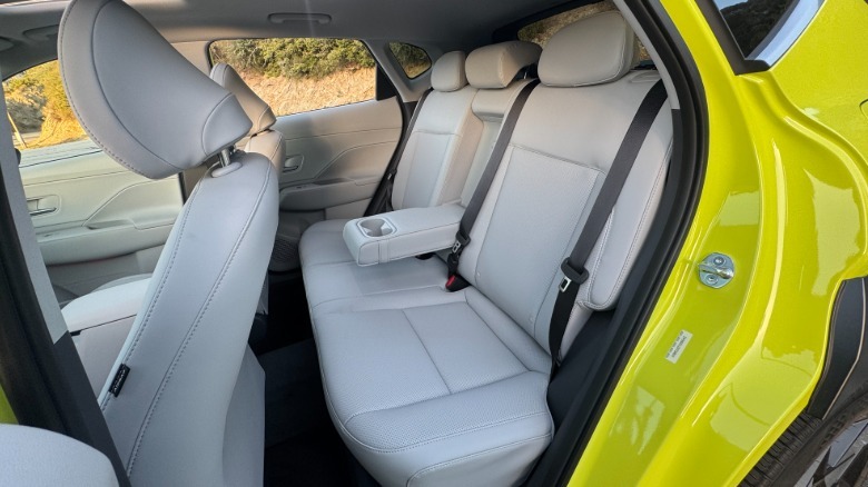 A photo looking in the rear driver's side door showing the white leather rear seats with the center arm rest/ cupholder folded down