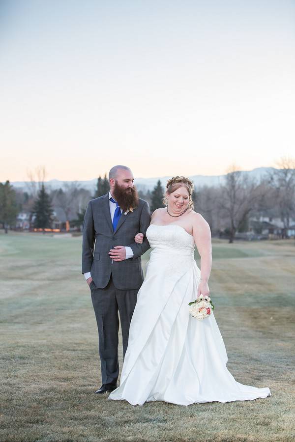Plus-size bride in strapless white satin A-line wedding dress walking hand-in-hand with groom outdoors