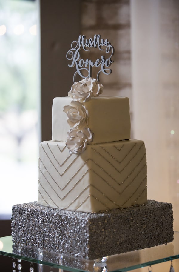 Two-tier wedding cake with a geometric chevron and art deco pattern in ivory fondant with gold and silver metallic accents