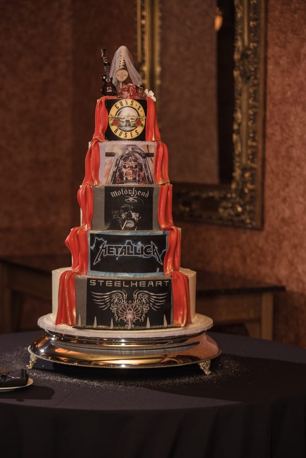 Five-tier custom wedding cake with each tier hand-decorated with iconic heavy metal band artwork and logos in a 1980s rock theme