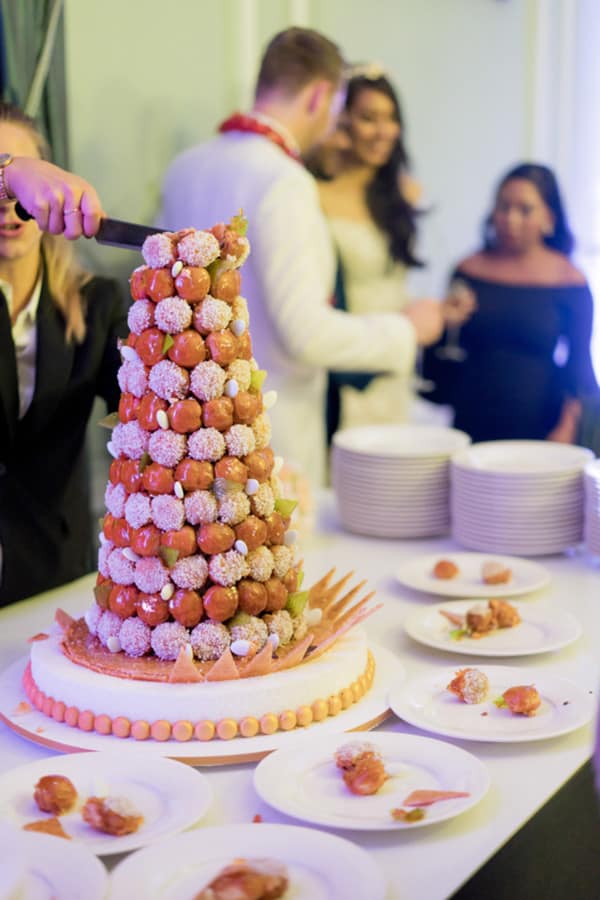Tall croquembouche wedding cake alternative made of cream puffs bound in caramel with floral accents at a Paris wedding reception