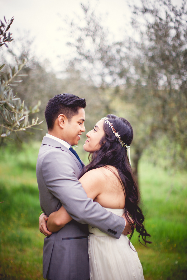 Couple in a face-to-face embrace, smiling at each other among olive trees in Tuscany