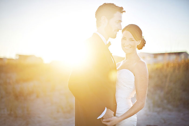 Bride and groom standing chest to chest in golden backlight, the groom gazing down