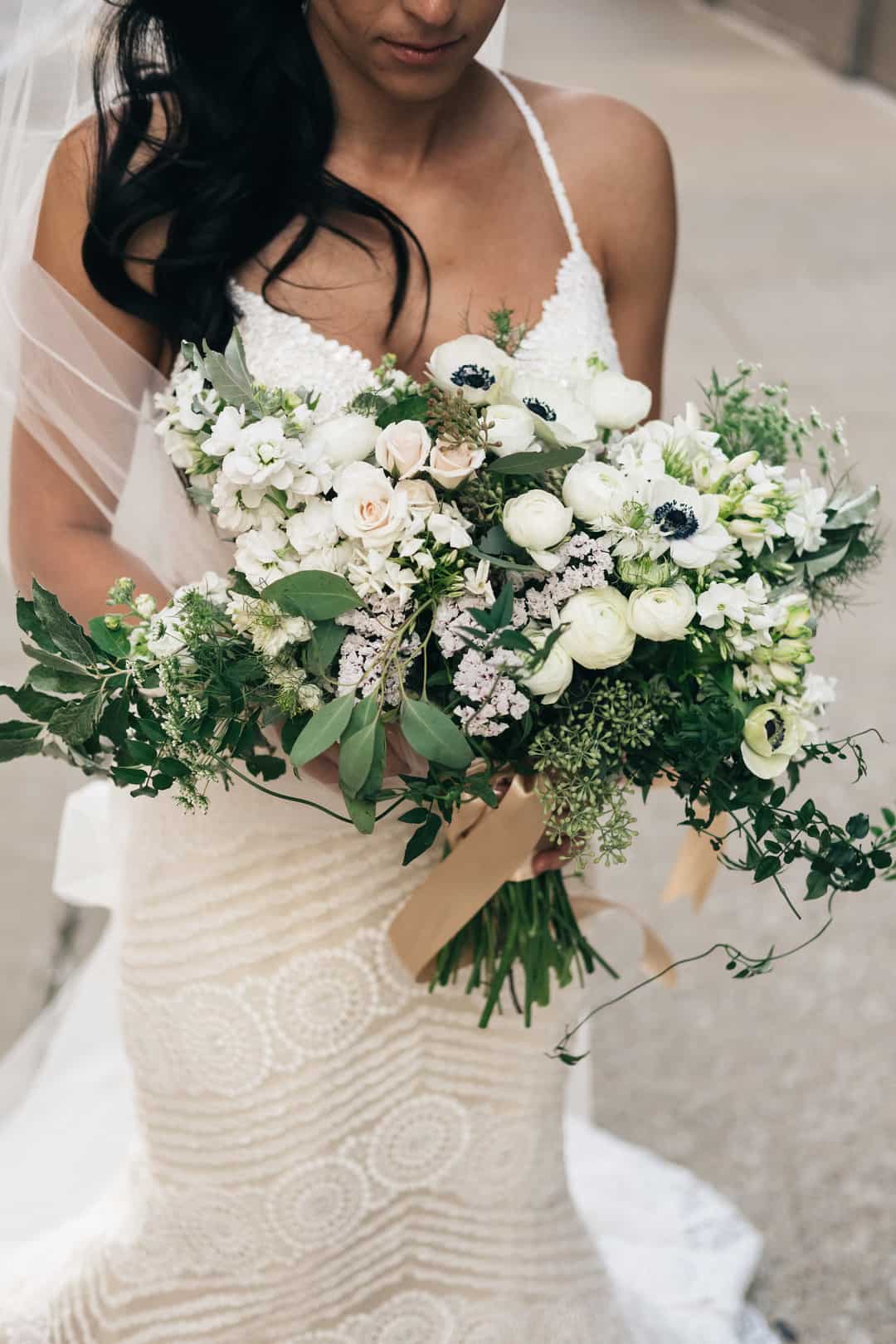 White ranunculus clustered with anemones, blush spray roses and stock