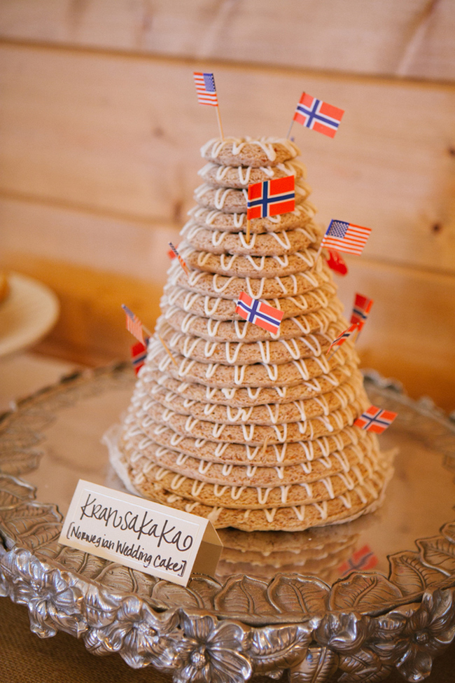 Tall cone-shaped Norwegian kransekake made of stacked iced almond rings, topped with small American and Norwegian flags