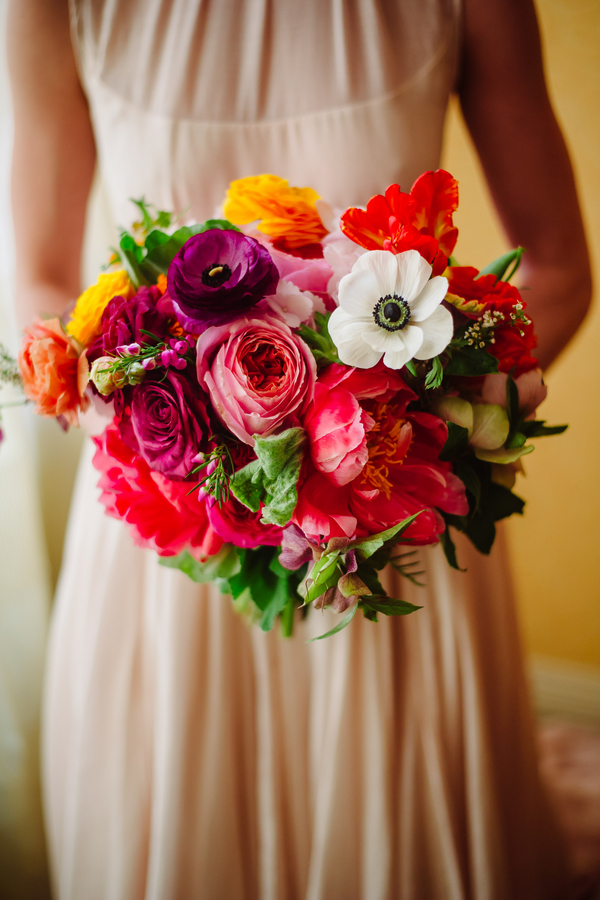 Jewel-toned bouquet with purple, orange and yellow ranunculus and a white anemone