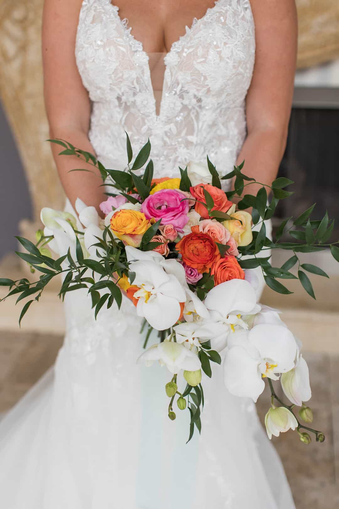 Vibrant bouquet with pink and orange ranunculus, orange roses and white orchids