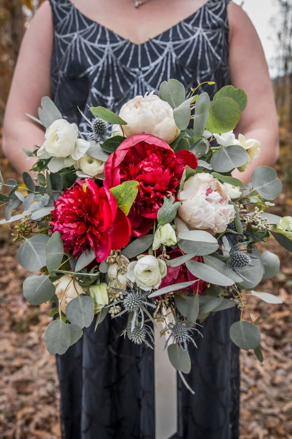 White ranunculus and red peonies with blue thistle and silvery eucalyptus
