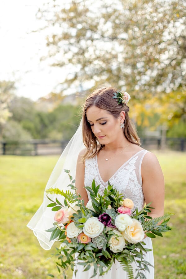Peach and coral ranunculus with cream roses, a burgundy anemone and succulents