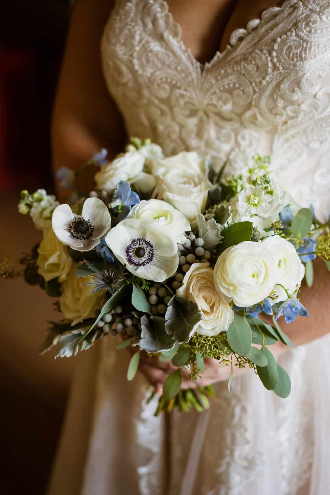 Close-up of white ranunculus and anemones with blue delphinium and eucalyptus