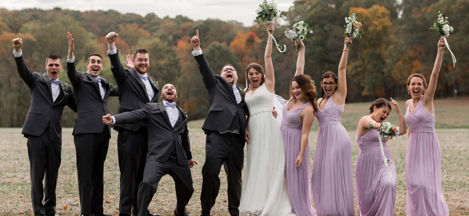Bridesmaids in lavender floor-length gowns cheering with bouquets raised