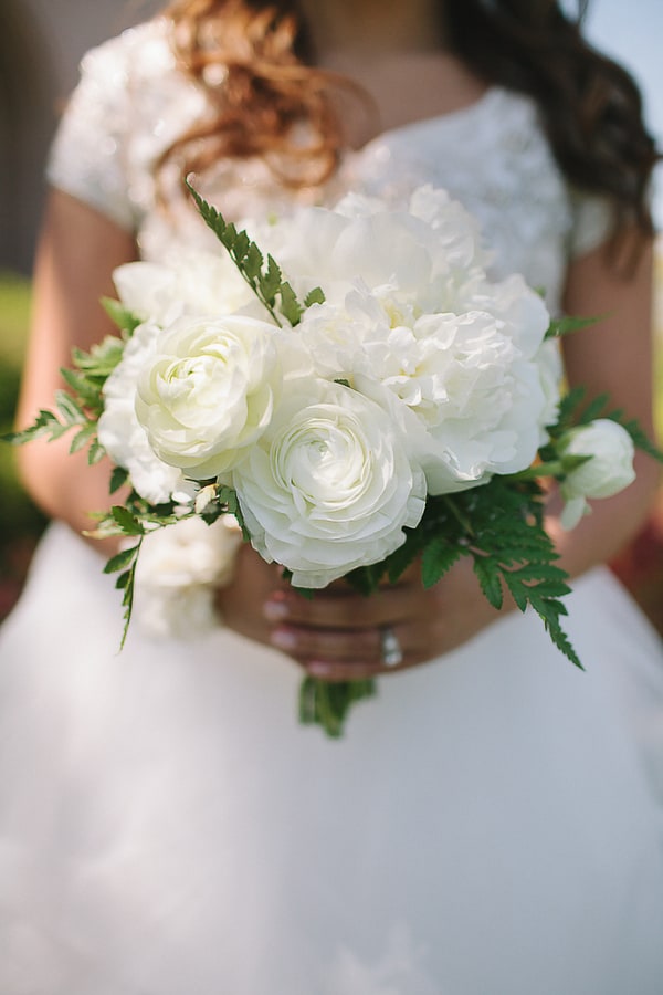 Small all-white bouquet of ranunculus and peonies with fern greenery
