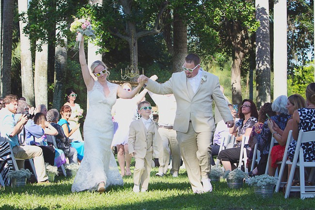 Bride and groom walking down the aisle in white sunglasses