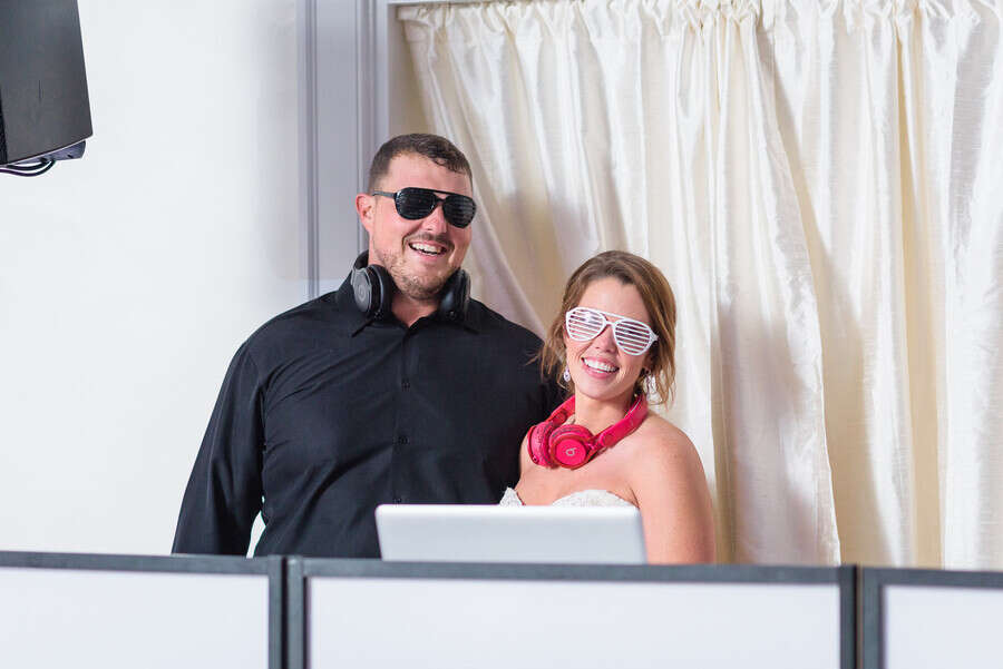 Bride and groom at the DJ booth wearing novelty sunglasses