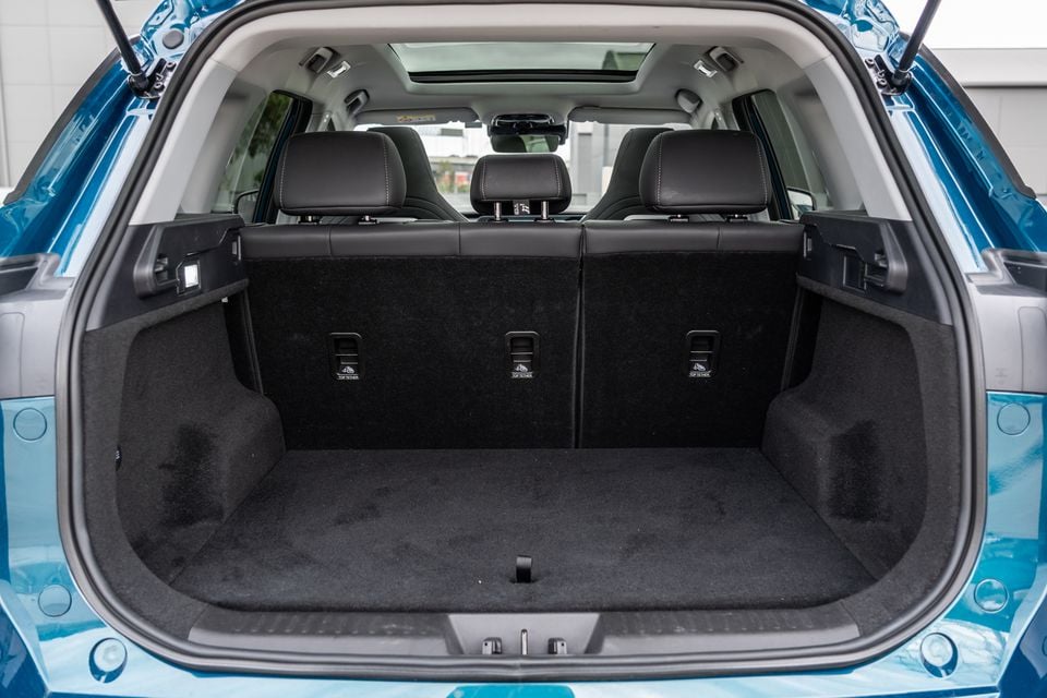 The empty boot of a blue Chery Tiggo 7 Super Hybrid SUV, showing carpet lining, three top-tether anchor points, and rear seats with leather headrests visible through the open tailgate.